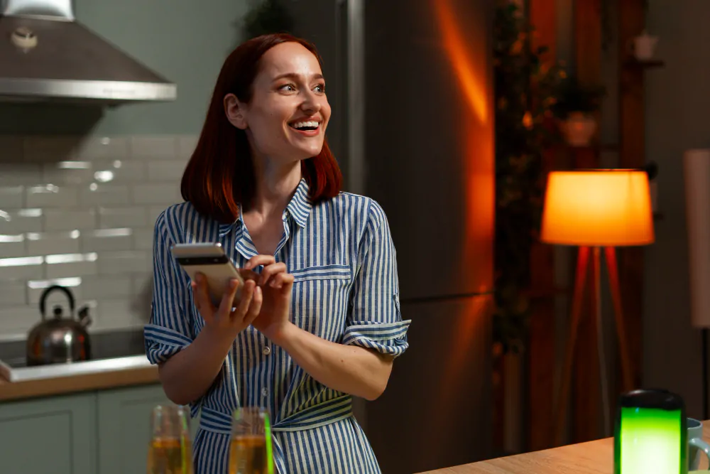 mulher na cozinha mexendo no celular e sorrindo